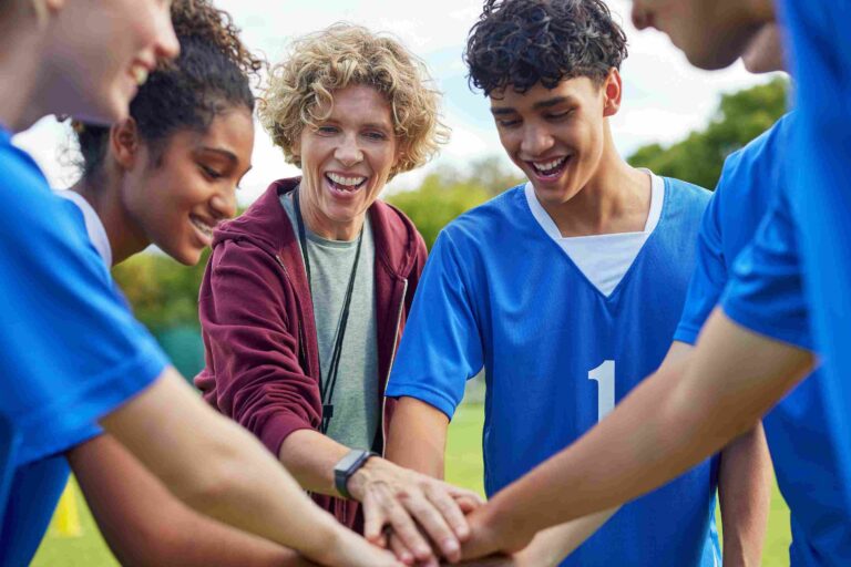 Studenti i trener okupljeni u timskom sportskom krugu na otvorenom